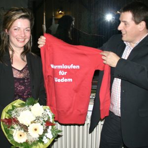 Jürgen Horn überreicht Kathrin Plotke ein Jogging-Shirt mit der Aufschrift: "Warmlaufen für Uedem".